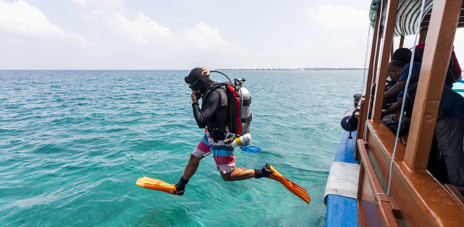 Academy ichthyologist Luiz Rocha in mid-air as he steps off dive boat in the Maldives