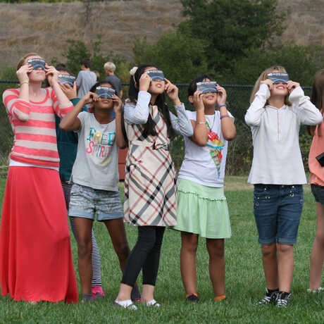 jóvenes observando el eclipse con lentes solares 