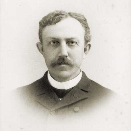 Sepia tone portrait of young, white man in suit with full mustache