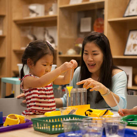 Toddler girl and mom play with science equipment in Naturalist Center