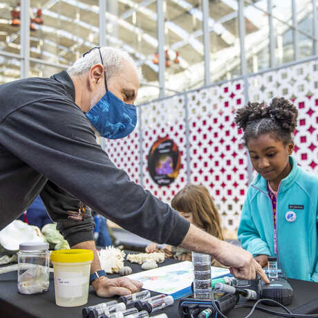 Aquarium curator Charles Delbeek demonstrates a science experiment to a young girl during Academy Day 2023