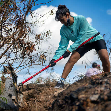 Volunteer woman cleans up trash in a park with a rake