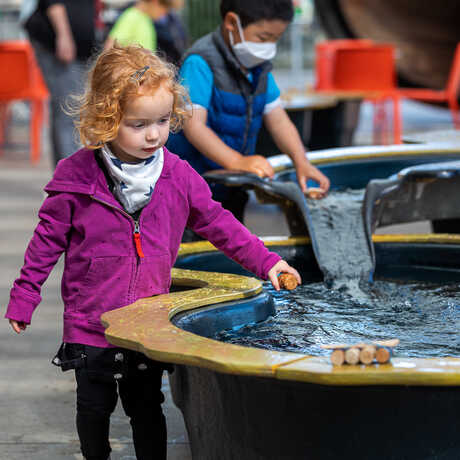 A young girl plays at the Riveropolis water table at the Academy