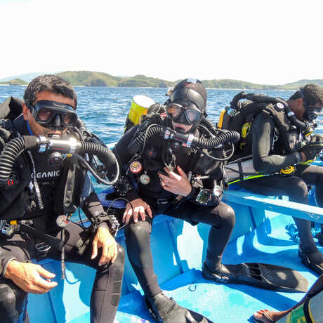 A trio of Academy scientists on a boat in scuba gear, ready to dive Palau.
