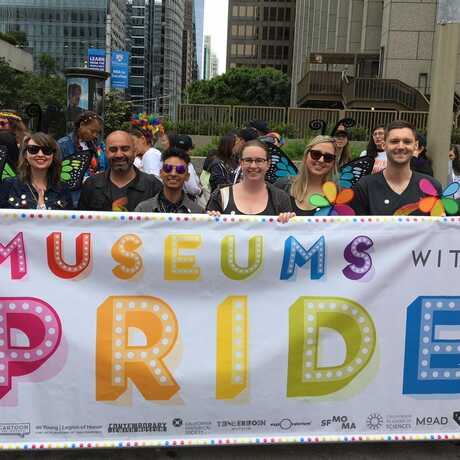 Pride club members march with a colorful banner 