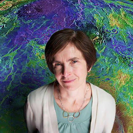Suzanne Smrekar stands before a color-coded, topographical map of Venus.