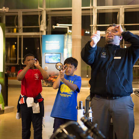 Academy staff demonstrates proper magnifying glass technique to youngsters