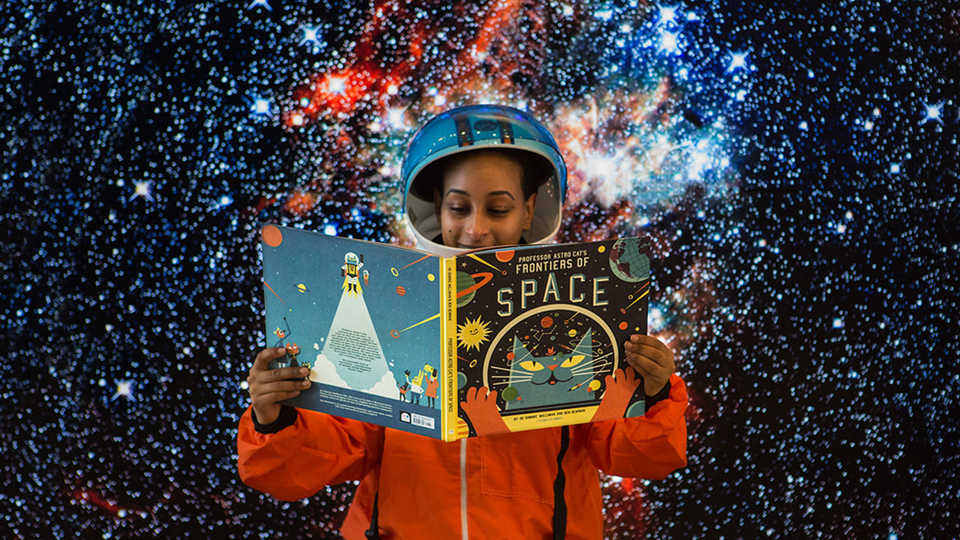 Astronaut holding storybook for interstellar story time