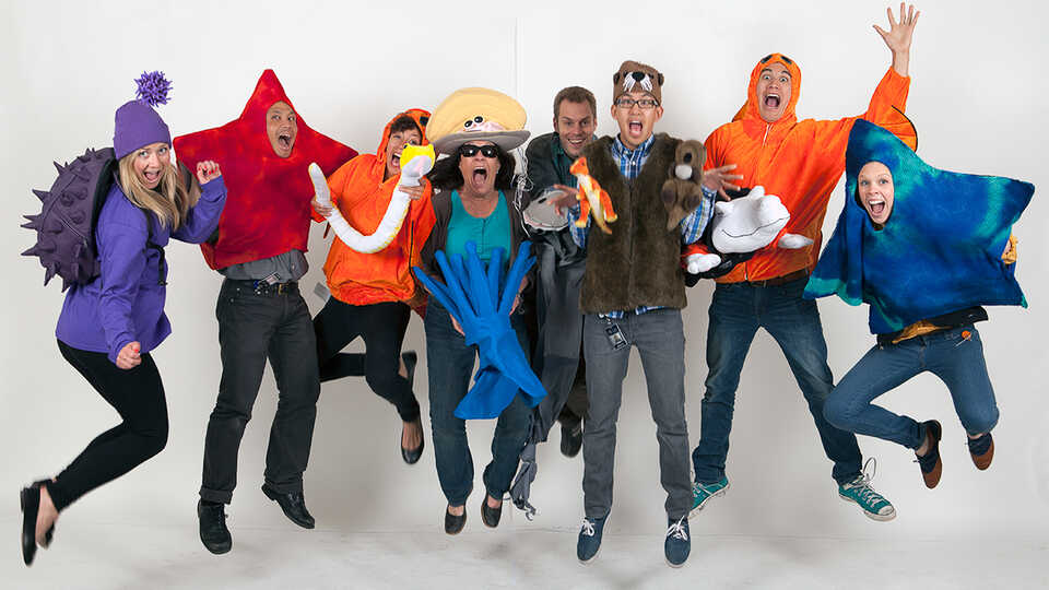 Staff in a variety of animal costumes joyously jump in midair