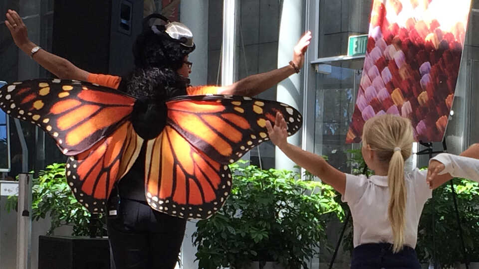 Presenter dressed as a butterfly "flying" with young children