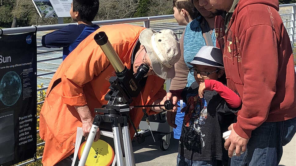 An Academy Docent helps Astronomy Day visitors observe the Sun safely.