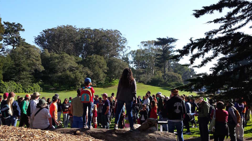 Woman addressing crowd of people in a park